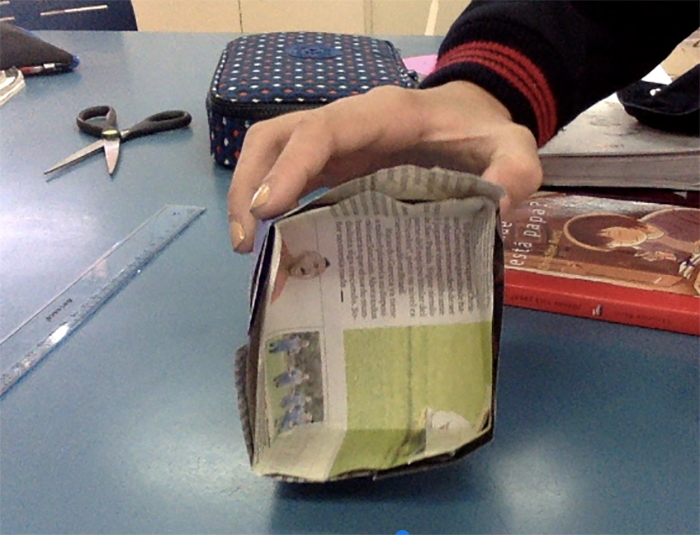 Student hand holding a newspaper water tank ready to test.