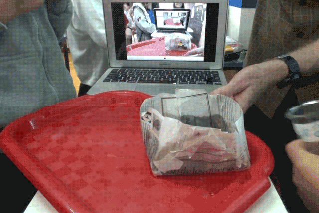 Animated demonstration of pouring water out of a newspaper water tank and into a graduated cylinder.