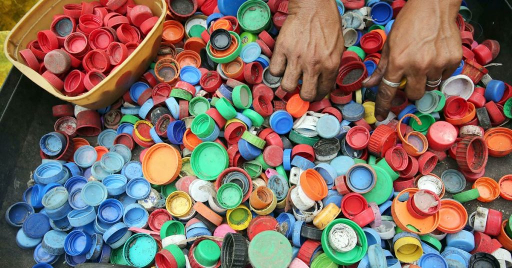 Sorting multiple bottle caps by type and color for reuse.